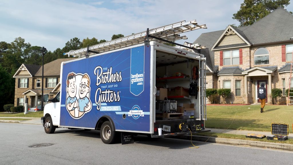 Brothers Gutters West Atlanta box truck parked at a job with the gutter machine open