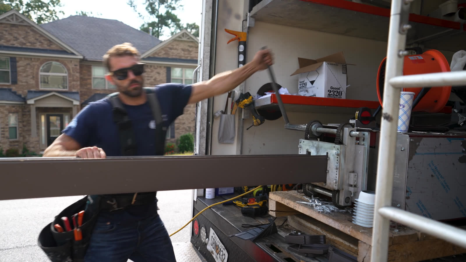Installer running a seamless brown gutter off the machine in the truck
