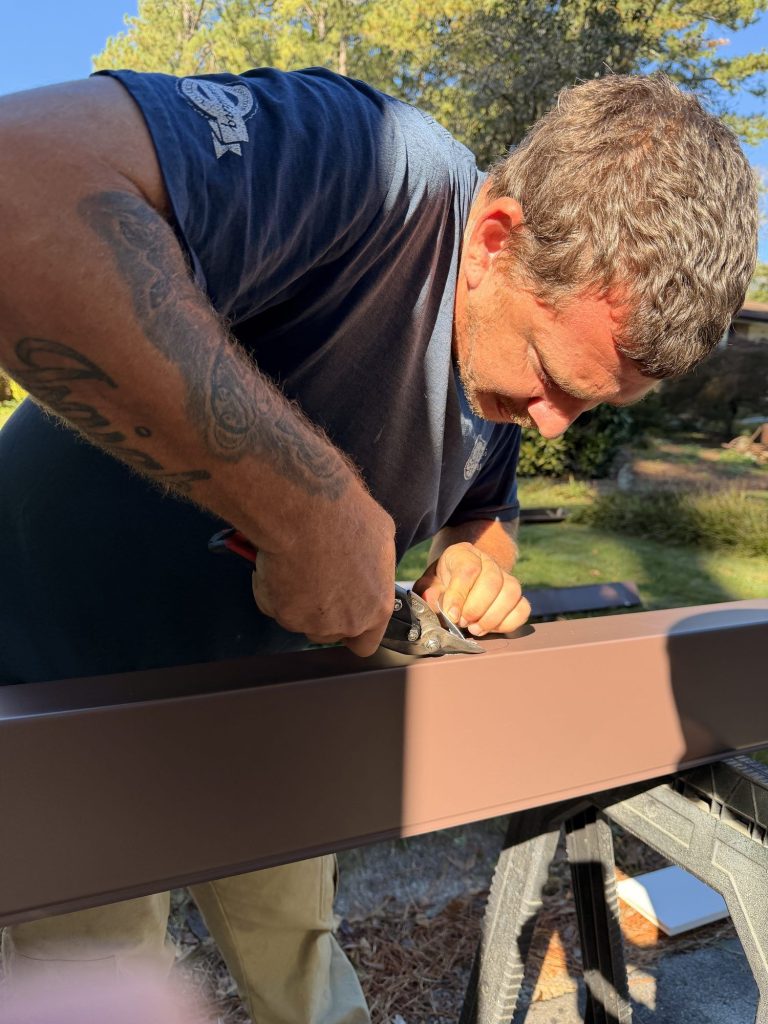 Installer crimping the end of a brown seamless gutter run in Smyrna