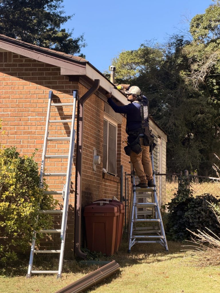 Installers on ladders working the gutter line of a brick ranch home in Smyrna