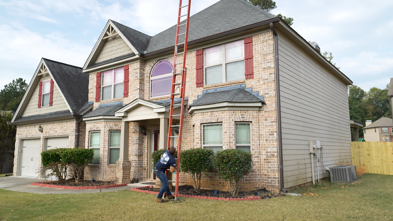 Installer setting up the ladder at a brick and siding home
