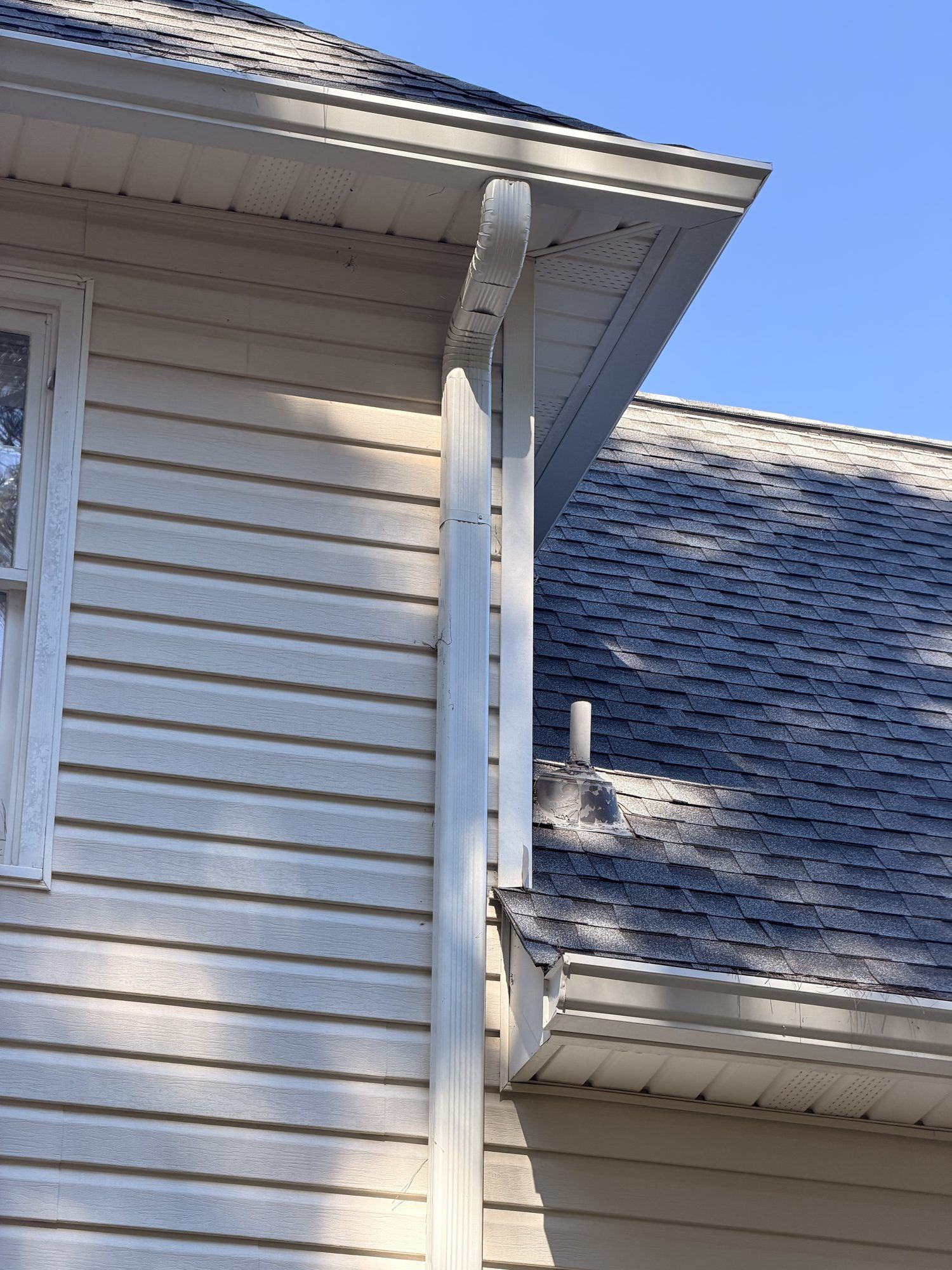 White downspout bringing an upper roof down onto a lower roof in Douglasville